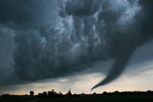 Image of dark skies and a tornado looking over a landscape.
