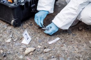 gloved technician collecting evidence at a crime scene