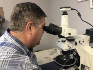 Image of Beton's Mark Lukkarila looking into his petrographic microscope.