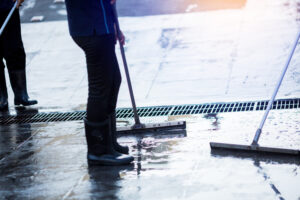 Squeegees being used to move water on a concrete floor towards the drain