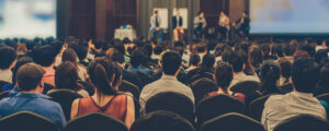 Panel of speakers in front of large audience